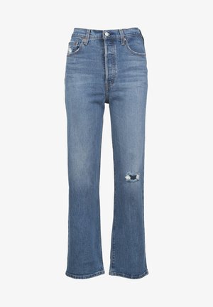 Jean en denim bleu à taille haute, coupe droite, style cinq poches, fermeture par boutons, avec une petite déchirure sur la cuisse droite.