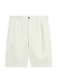 Shorts beige clair fabriqués dans un tissu texturé. Dotés d'un pli avant, de passants de ceinture et d'une fermeture à bouton noir. Fins au genou.