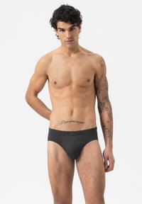 Zwarte katoenen boxershort met een snug fit, elastische tailleband en een minimalistisch ontwerp. Het model heeft een getraind lichaam en een lichte huid.