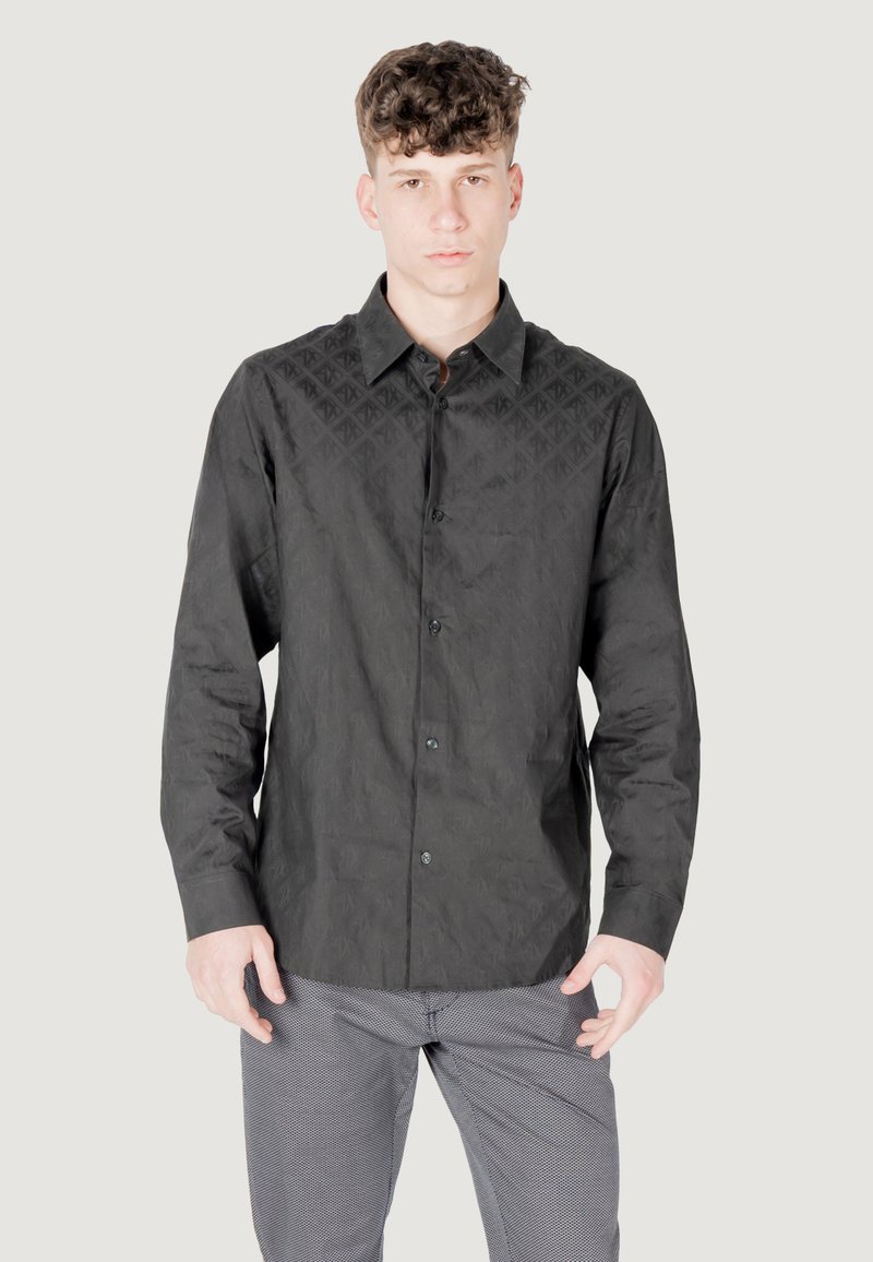 Camicia nera con bottoni, realizzata in tessuto testurizzato, caratterizzata da un motivo geometrico sulle spalle. Include un colletto all'americana e una tasca sul petto.