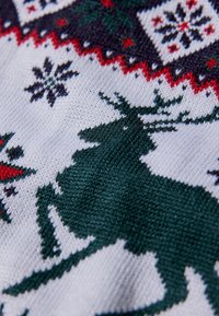 Tecido de malha com uma base branca apresenta uma silhueta de rena verde, detalhes em vermelho e padrões de inverno, como flocos de neve e designs geométricos.