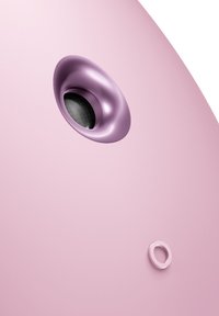 Produit rose arrondi avec une texture lisse, présentant une ouverture circulaire violette plus foncée et un petit détail en forme d'anneau rose à proximité.