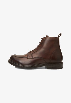 Rjave usnjene gležnarje z gladko površino, okroglo konico, vezalnim dizajnom in majhnim trakom za pomoč pri obuvanju na peti. Guma podplat za oprijem.