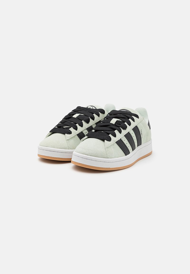Le sneaker verde in suede presentano lacci neri, tre strisce laterali nere e una suola in gomma bianca con un accento in gomma color gum alla base.