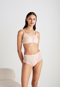 Peachfarget bh med glat stoff og V-formet utringning, kombinert med matchende høyhåndt briefs med bølgemønster.