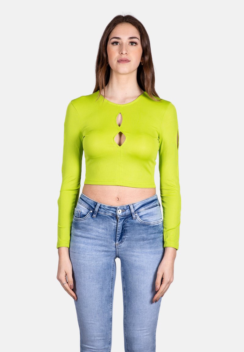 Top corto a maniche lunghe a coste verde lime con tre tagli a chiave; abbinato a jeans aderenti azzurri, vista frontale.
