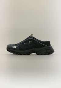 Μαύρο πεζοπορικό παπούτσι χωρίς κορδόνια με ανθεκτική σόλα, πάνελς από διχτυωτό υλικό και το λογότυπο "The North Face" στο μπροστινό μέρος, σε ουδέτερο φόντο.