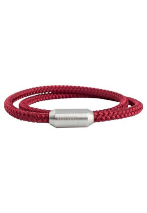 Červený pletený náramek s válcovým stříbrným magnetickým zapínáním na bílém pozadí.