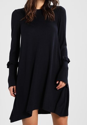 Zwarte jurk met lange mouwen, gemaakt van gebreide stof, met een losse pasvorm, gerimpelde mouwaccenten en een asymmetrische zoom.