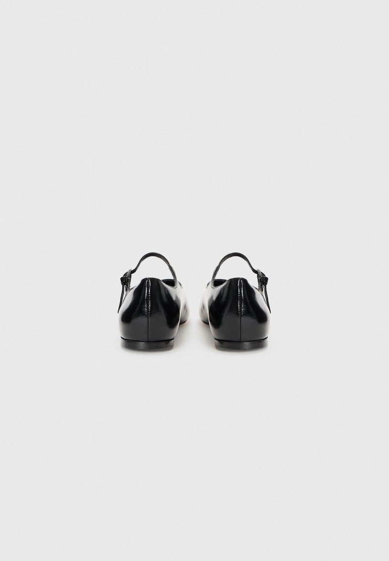 Schwarze Lederschuhe mit glatter Textur, rundem Zehenbereich und einem Rückengurt. Flache Sohle und minimalistisches Design.