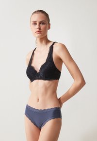 Svart blonde-BH med bølgende kanter, med dyp V-hals og tynne stropper, sammen med marineblå truser med blondekant.