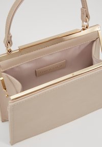 Beżowa torebka z złotymi akcentami, o strukturalnym wzornictwie i gładkiej teksturze. Posiada wewnętrzną kieszeń oraz szczegóły przeszycia.