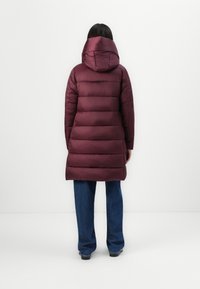 Bordeauxkleurige pufferjas met een capuchon, voorzien van verticale gestikte secties, een middellange pasvorm en een gladde, glanzende textuur.