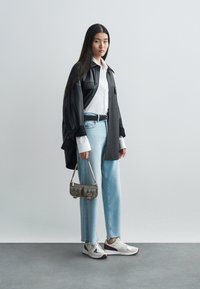 Black oversized shirt, white button-up, light blue jeans, grey handbag, and grey and white sneakers with textured design.