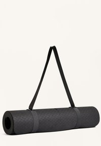 Svart yogamatta rullad, med en texturerad yta med ett geometriskt mönster. Säkerställd med en svart rem för bärande.