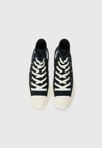 Svarta högre sneakers i canvas, med vit gummitå, snören och dekorativ sömnad, som har färgglada accenter på sidorna.