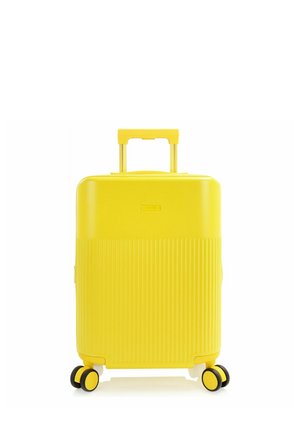 Gelber Hartschalenkoffer mit vier Schwenkrädern und ausgezogenem Teleskopgriff, auf weißem Hintergrund aufrecht stehend.