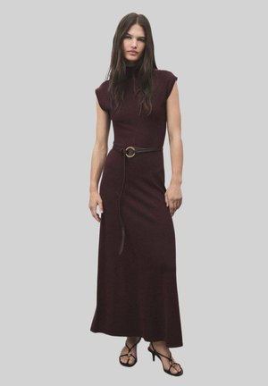 Burgundy knit dress with a high neck, cap sleeves, and a fitted waist, accented by a brown belt with a circular buckle. Long, flowy hem.