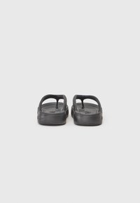 Svarte flip-flops laget av gummi, med flat såle, to remmer for tå- og bue støtte, og teksturert fotbed for grep.
