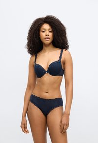 Σετ εσωρούχων σε ναυτικό μπλε με σουτιέν διακοσμημένο με δαντέλα και ενισχυμένες θήκες, συνοδευόμενο από μπικίνι σλιπ σε ίδιο στυλ. Το ύφασμα έχει απαλό υφή με μικρά σχέδια.