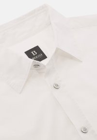 Witte katoenen overhemd met puntkraag, voorzien van een zwart label met het "BOGGI"-logo en twee witte knopen aan de voorkant.