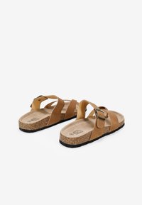 Sandali in pelle marrone con suole in sughero, caratterizzati da due cinghie sovrapposte e una fibbia metallica quadrata per una vestibilità regolabile.