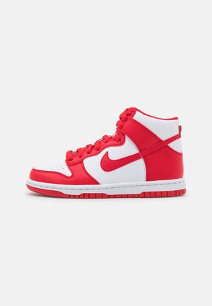 Wysokie buty sportowe Nike z białymi i czerwonymi skórzanymi panelami, czerwonymi sznurowadlami i logo Nike na jednolitym białym tle.