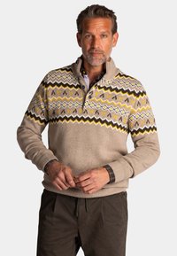 Beige pullover trui met een gestreepte schouderpartij met zigzagpatronen in geel, bruin en wit. Halflange knoopsluiting bij de kraag en boordjes aan de mouwen.