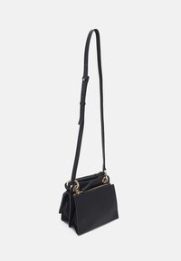 Borsa a spalla in pelle nera con tracolla regolabile, due scomparti, finitura texturizzata, hardware dorato e chiusura con zip su un lato.