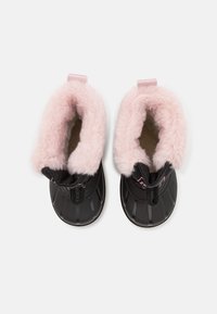 Černé boty s měkkou růžovou umělou kožešinou, zaoblenou špičkou, texturovaným svrškem a poutky na vytažení; navrženy pro teplo a snadné obouvání.