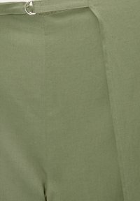 Tissu vert avec une texture lisse et un détail subtil de tissage. Il présente une couture latérale et un accent matériel circulaire à la taille.