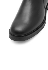 Mustad musta nahast pahkluboot, ümarate varvastega, sileda tekstuuriga ja madala kummist kontsaga. Suurtäpsusega disain, millel on minimaalsed õmbluse detailid.