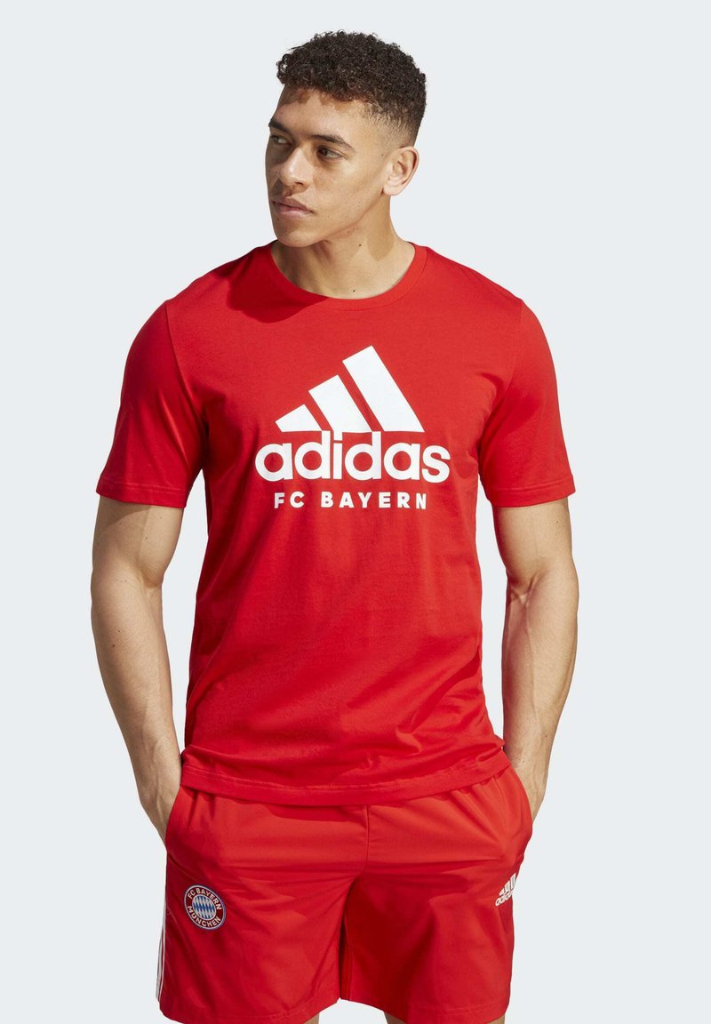 La camiseta roja de Adidas del FC Bayern presenta un logo blanco y tres franjas. Combinada con pantalones cortos rojos a juego, exhibe un look atlético clásico.
