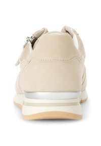 Schuh mit weichem, beigem Wildleder-Außenmaterial, das an der Ferse mit einem silbernen Akzent und seitlichen Netzdetails versehen ist. Flache Gummisohle.