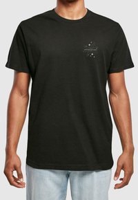 Zwart katoenen T-shirt met korte mouwen. Voorzien van een klein wit grafisch ontwerp van sterren en tekst op het linkerborstgebied. Klassieke pasvorm.