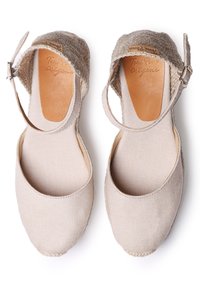 Šviesiai rudos drobės espadrilės su kulkšnies dirželiu, džutų detalėmis ant kulno, guminėmis padais, lygiu paviršiumi ir apvaliu pirštu.