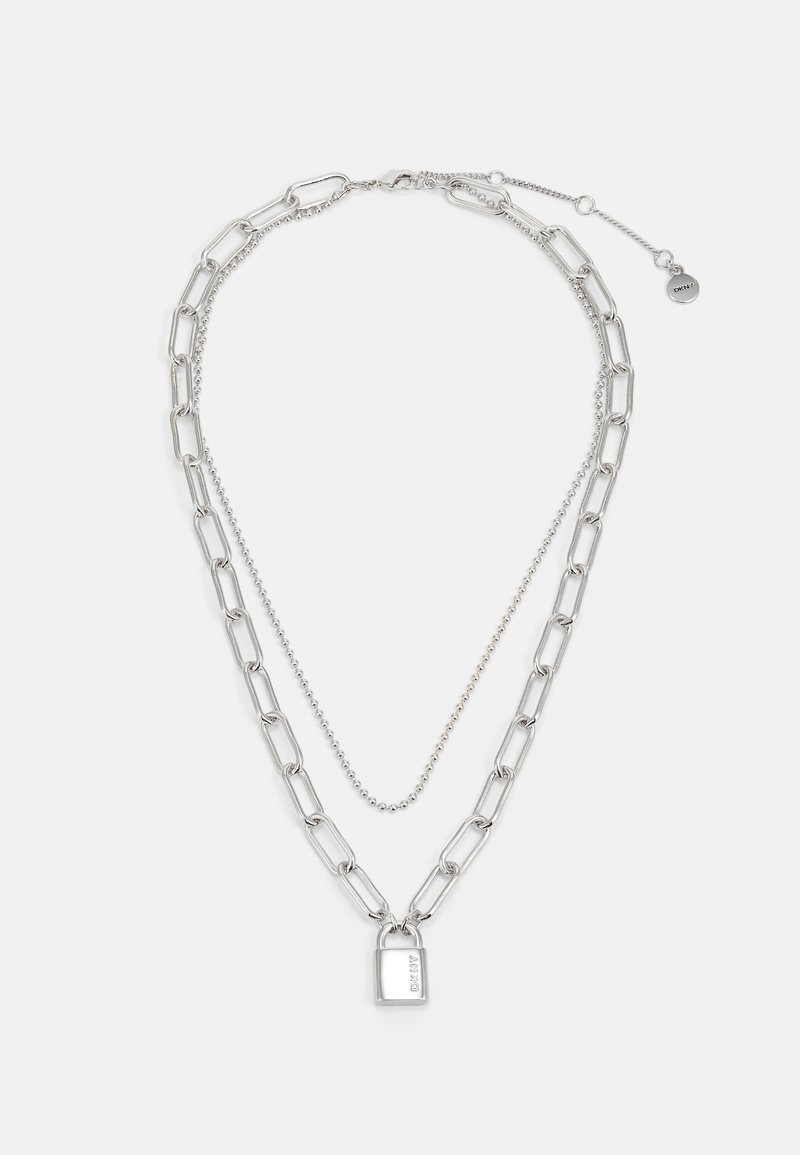 Stříbrný řetízek s dvěma vrstvami: velký článkový řetěz a korálkový řetěz, se malým visacím zámkem jako přívěskem. Strukturální kovový povrch.