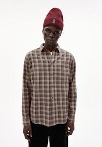 Bruin en crème geblokt overhemd met een zak, button-down kraag en lange mouwen, gedragen met een bordeaux ribgebreide muts.