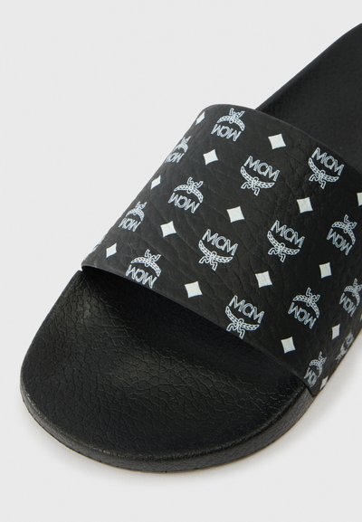 Chinelo preto slide com palmilha texturizada e faixa larga apresentando logótipos MCM brancos repetidos e formas de diamante.