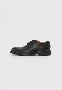 Czarne skórzane buty eleganckie z okrągłym noskiem, wiązane, z przeszyciami wokół podeszwy i teksturowaną gumową podeszwą.