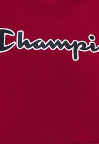 Tela de algodón roja con el logotipo bordado de "Champion" en negro y blanco. Textura suave con un acabado ligeramente brillante.