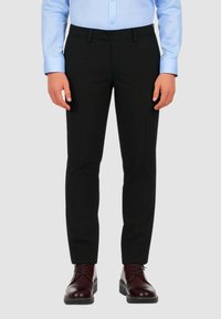 Pantaloni neri su misura con vestibilità slim, dotati di tasche anteriori e una superficie liscia. Abbinati a scarpe stringate bordeaux.