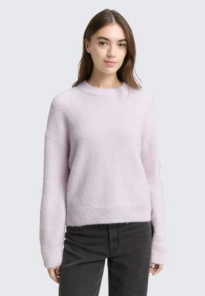 Pull en tricot rose clair avec un col rond, des poignets et un ourlet côtelés. Texture douce, coupe décontractée, associé à un jean gris foncé.