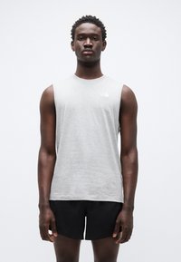 Γκρι αμάνικη μπλούζα από ελαφρύ υλικό, με στρογγυλή λαιμόκοψη και μικρό λευκό λογότυπο στο στήθος, σε συνδυασμό με μαύρο σορτς.