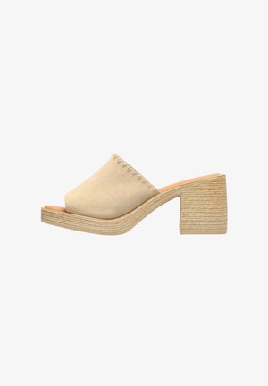 Mule beige de ante con puntera abierta, tacón bajo grueso tejido y diseño slip-on.
