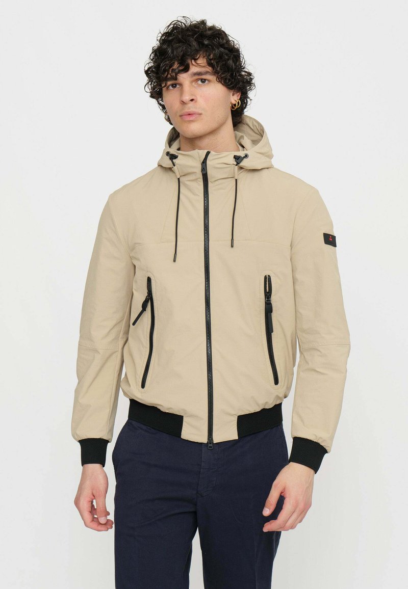 Giacca cappuccio beige chiaro con coulisse regolabile, zip nera e due tasche frontali; polsini ed orlo inferiore elasticizzati per una vestibilità aderente.