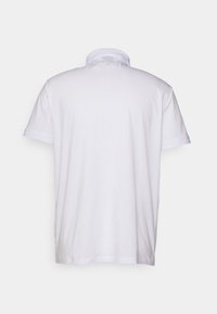 Vit polo skjorta med klassisk krage och korta ärmar. Slät textur med kontrasterande färg på ärmsluten. Visad bakifrån.