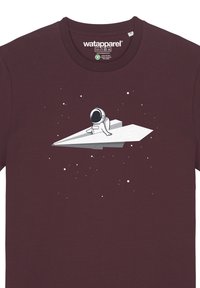 Bordeaux T-shirt met een witte astronautgrafiek die op een papieren vliegtuigje zit, omgeven door kleine witte sterren op een donkere achtergrond.