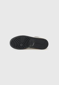Svart sneaker sula med cirkulära mönster och räfflor. Har en texturerad yta och kontrasterande ljusa accenter längs sidorna.