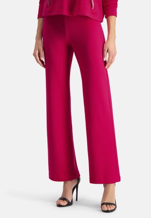 Fuchsia wijde broek van zacht materiaal met een gladde textuur, met een hoge taille en strakke lijnen, gecombineerd met zwarte stiletto hakken.